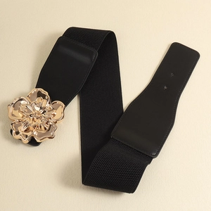 Détail d'une large ceinture élastique ornée d'une grande boucle fleur en métal doré poli