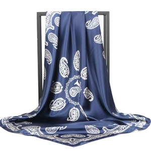 Elegant blue paisley satin square silk scarf displayed on a minimalist frame with drape