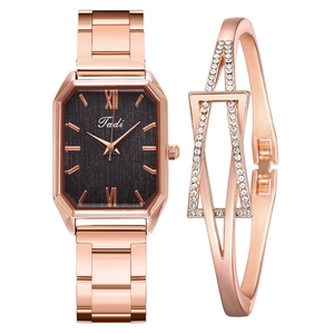 Detail of rose gold rectangular watch with crystal bangle set on a white background