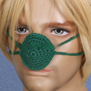 Detail shot of a handmade green crochet nose warmer with adjustable ties on a model head