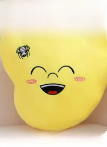 Close-up of yellow plush cushion showing soft texture and smiling embroidery detail