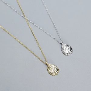 Macro detail of gold and silver teardrop pendants with radiant sunburst cubic zirconia