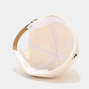 Detailweergave van een gebroken witte katoenen docker-hoed met zwart b-borduurwerk.