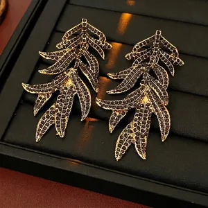 Vintage gold leaf tassel earrings with black rhinestones on a luxury jewelry tray