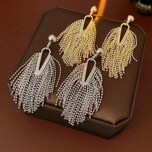 Detailed close-up of gold and silver tassel earrings on a brown leather jewelry box