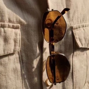 Geometrische Retro-Sonnenbrille in Schildpatt-Optik an einer beigen Hemdtasche