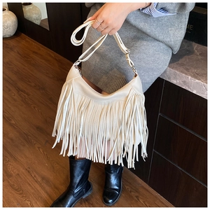 Detail of bohemian cream fringe shoulder bag with high-quality litchi grain leather texture