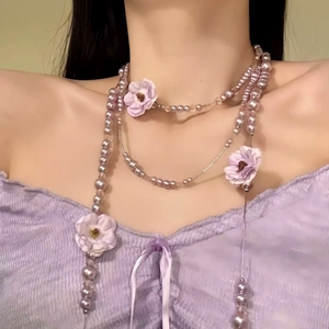 Nahaufnahme einer lavendelfarbenen Perlenkette mit Stoffblumen an einem Model