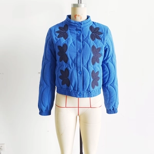 Close-up of royal blue quilted jacket featuring retro ethnic floral embroidery and stand collar