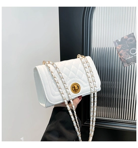 Detail of white quilted crossbody bag featuring a golden twist lock and metal chain strap