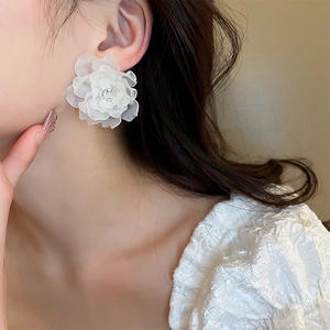 Elegante weiße Acryl-Blumenohrringe mit Diamantzentrum, getragen von einem Modell
