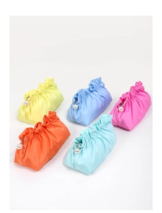 Dettaglio di pochette cosmetiche plissettate colorate con eleganti ciondoli a perla