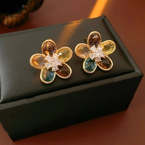 Macro shot of gold flower earrings with multicolored crystals on black leather jewelry box