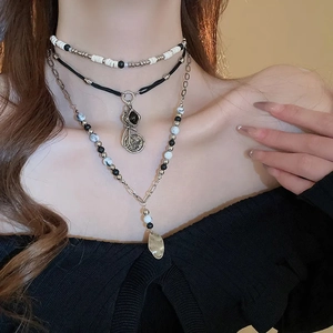 Detail view of layered bohemian necklace with beads, geometric pendant and leaf charm