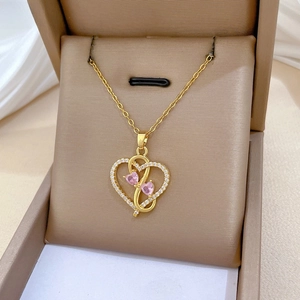 Detailed close-up of a gold heart pendant with pink crystals and small diamonds