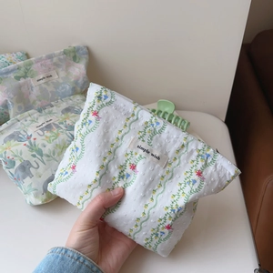 Close-up of cotton cosmetic bag featuring floral embroidery and simple wish label
