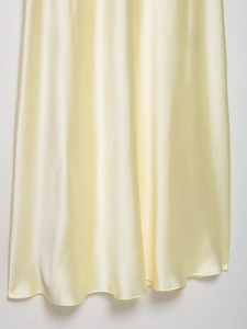 Detail of light yellow satin midi skirt showing smooth silky texture and soft drape