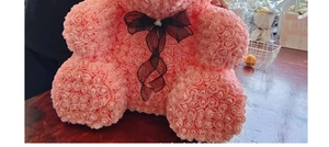 Detail shot of a large pink foam rose bear with a black ribbon bow on a wooden surface