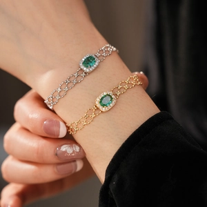 Detail of vintage gold and silver bracelets with oval green zircon in halo setting