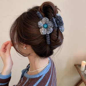 Detail of dark blue plaid fabric hair claw clip with a grey wool flower on long hair
