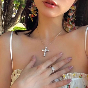 Silver stainless steel cross necklace with zircon pendant worn by a model in nature