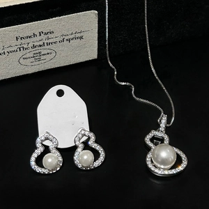 Macro shot of silver gourd necklace and earrings set with zircons and pearls