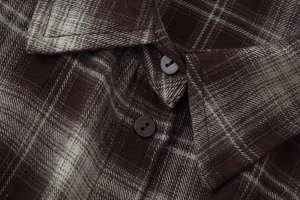 Macro shot of plaid shirt collar with detailed buttons and brown woven fabric texture