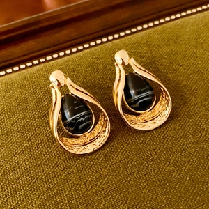 Detail view of gold teardrop earrings featuring black agate stone and vintage texture