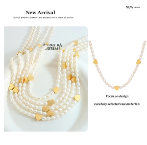 Detail of freshwater pearl necklace featuring polished gold heart-shaped charms