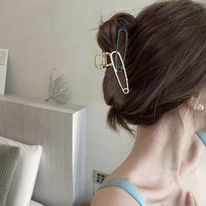 Detailed view of the safety pin style metal hair claw clip in white and dark green colors