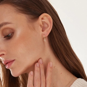 Classic gold hoop earrings with micro-set zircon cross pendant on elegant female model