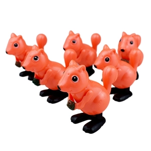 Close-up of orange wind-up squirrels holding pine cones with selective focus detail