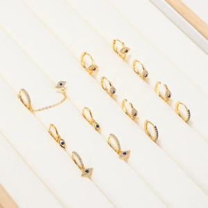 Golden evil eye earrings set with blue zircons and chains displayed in a velvet box