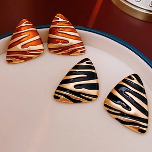 Macro shot of vintage triangle stud earrings with gold plating and animal print patterns