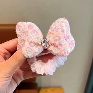 Detail of pink bow hair tie with colorful sequins and a water drop diamond center
