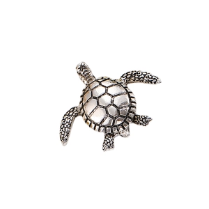 Gros plan d'une broche tortue vintage en argent avec motifs de carapace hexagonaux