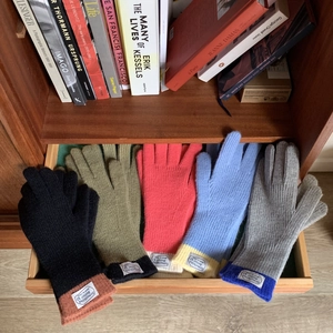 Detailed view of color-blocked knit gloves in five colors arranged in a wooden drawer