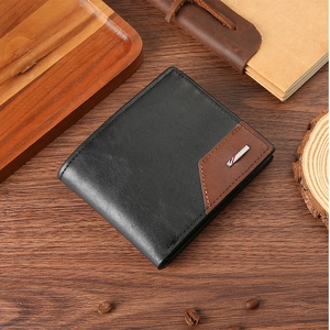 Détail du portefeuille en cuir avec coutures contrastées et logo en métal sur bois