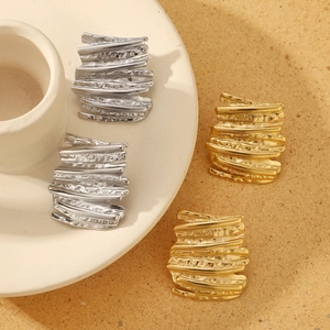 Detail of gold and silver hammered square earrings with textured irregular metal surface