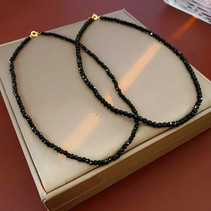Macro detail of multifaceted black crystal beads necklace with a golden spring clasp