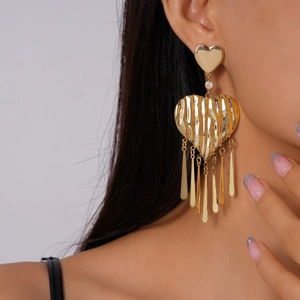 Close-up of golden heart tassel earrings with pleated texture worn by a model