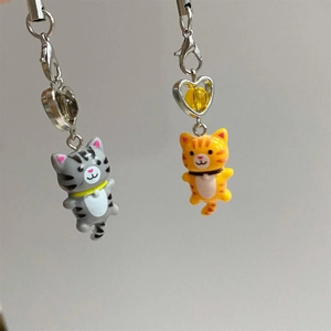 Detail of grey and orange striped cat pendants with silver metal clasps and tiny bells