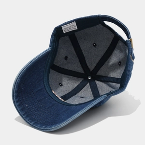 Detail of internal cotton stitching and adjustable metal buckle on blue denim baseball cap