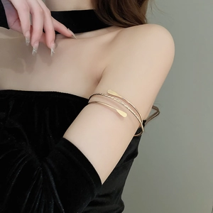 Close-up of golden multi-layer spiral arm cuff with twisted metal texture on female upper arm