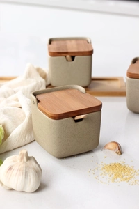 Detail of speckled ceramic seasoning jar with wooden lid and spoon in a kitchen setting
