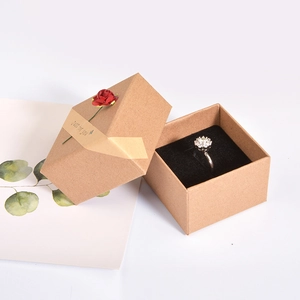 Kraft paper jewelry box with red rose and Just for You ribbon holding a silver flower ring
