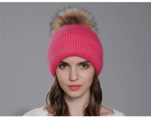 Détail d'un bonnet en tricot fuchsia avec un grand pompon en fourrure naturelle