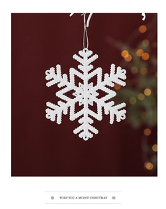 Close-up of white glitter snowflake ornament with silver string on festive red background