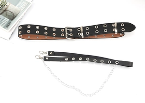 Detail of a black punk leather belt with double silver eyelets and a detachable metal chain