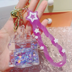 Close-up of a castle drifting bottle keychain with purple glitter and gold bell charm